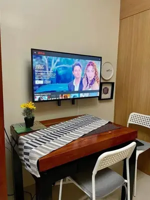 a desk with a keyboard and a television on a wall at Darren Staycation in Manila