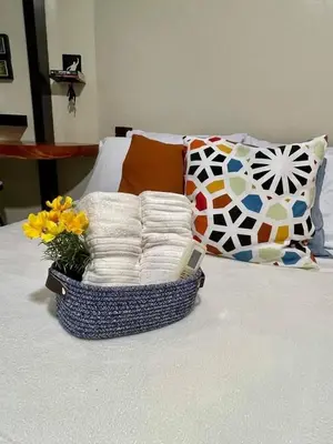 a basket of pillows and a vase with flowers on a bed at Darren Staycation in Manila