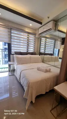a large white bed in a room with windows at Cozy new studio walk to Mall of Asia with balcony in Sampong