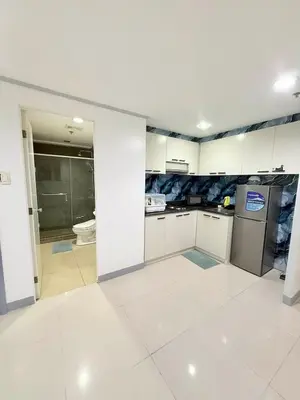 a kitchen with white cabinets and a white tile floor at Zion Staycation at Sea Residences in Manila