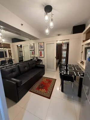 a living room with a black couch and a table at Zion Staycation at Sea Residences in Manila