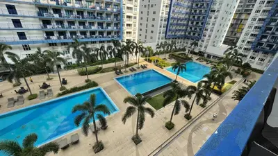 an overhead view of a large swimming pool with palm trees at Zion Staycation at Sea Residences in Manila