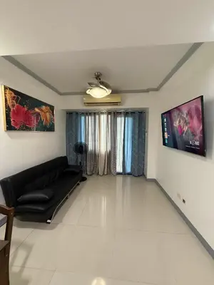 a living room with a black couch and a window at Zion Staycation at Sea Residences in Manila