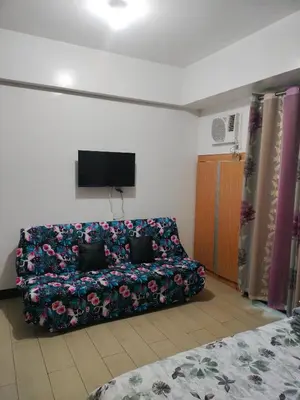 a couch sitting in a living room with a tv at Rqui Condotel at Newport Pasay City in Manila