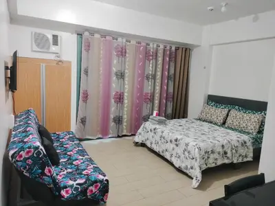 a bedroom with a bed and a couch and curtains at Rqui Condotel at Newport Pasay City in Manila