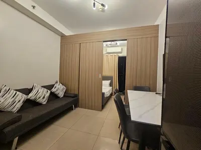 a living room with a black couch and a bedroom at The Executive Suites at Shore 2 Residences in Manila