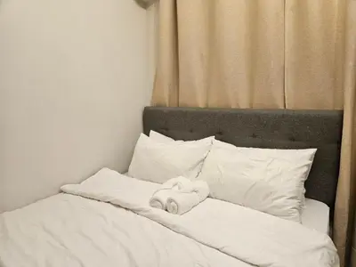 a stuffed animal laying on a bed with pillows at The Executive Suites at Shore 2 Residences in Manila