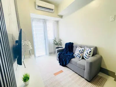 a living room with a couch and a tv at Shore 3 Residences Spacious & Spotless 1BR unit near airport MOA SMX in Manila