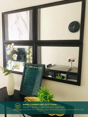 a desk with a computer and a window with a clock at Shore 3 Residences Spacious & Spotless 1BR unit near airport MOA SMX in Manila