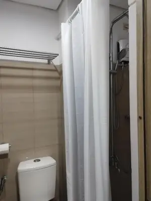 a bathroom with a white shower curtain and a toilet at Larsie's Place in Manila