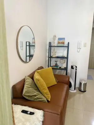 a living room with a brown couch and a mirror at Larsie's Place in Manila