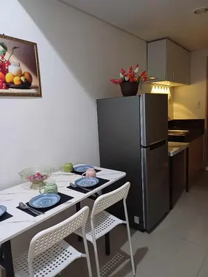 a kitchen with a table with two chairs and a refrigerator at 1BR in Leaf Residences in Manila