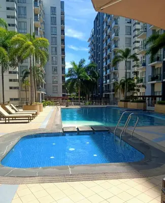 a swimming pool with palm trees and buildings at Comin'Joy Condotel at ONE PALM TREE VILLAS in Manila