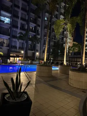 a courtyard with palm trees and a swimming pool at night at Comin'Joy Condotel at ONE PALM TREE VILLAS in Manila