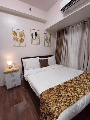 a bedroom with a large bed and a window at CHIC 1 BR in Air Residences in Manila