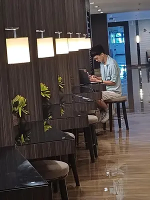 a man sitting at a bar using a laptop at CHIC 1 BR in Air Residences in Manila