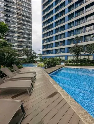 a swimming pool with chaise lounge chairs next to a building at CHIC 1 BR in Air Residences in Manila