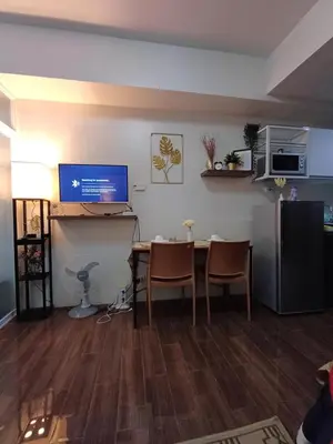 a living room with a table and a desk with a computer at CHIC 1 BR in Air Residences in Manila