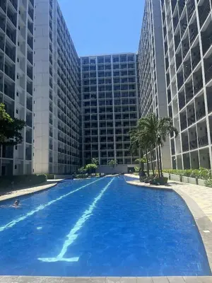 a large swimming pool in front of a tall building at Modern Sanctuary Near - MOA in Manila