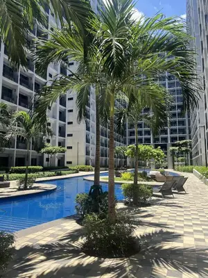 a palm tree in front of a large building at Modern Sanctuary Near - MOA in Manila