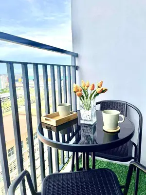 a table with two cups and flowers on a balcony at Modern Sanctuary Near - MOA in Manila