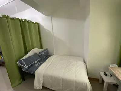 a small bedroom with a bed with green curtains at Gen coZy Condo Stay by Victoria de Manila Tower in Manila
