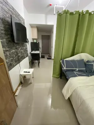 a room with a bed and a television and a table at Gen coZy Condo Stay by Victoria de Manila Tower in Manila