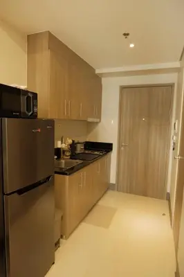 a kitchen with wooden cabinets and a stainless steel refrigerator at The Metro Suite - 1BR Condo 36F with City View in Manila