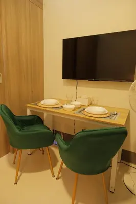 a table with two green chairs and a television on a wall at The Metro Suite - 1BR Condo 36F with City View in Manila