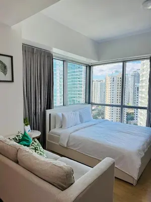 a bedroom with a large bed and a couch at Avant at the Fort BGC with King Bed and Motorized Curtains & 65 in TV in Manila