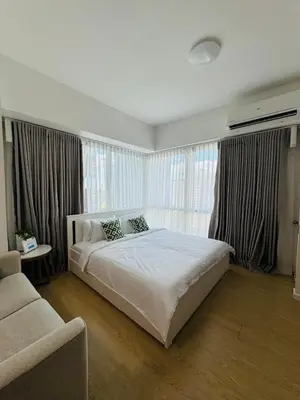 a bedroom with a large bed and a couch at Avant at the Fort BGC with King Bed and Motorized Curtains & 65 in TV in Manila