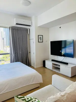 a bedroom with a bed and a flat screen tv at Avant at the Fort BGC with King Bed and Motorized Curtains & 65 in TV in Manila