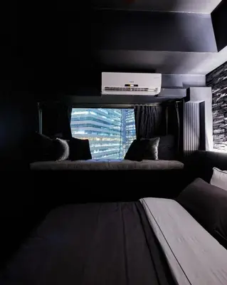 a dark room with a couch and a window at Luxury Condo in the heart of BGC in Manila