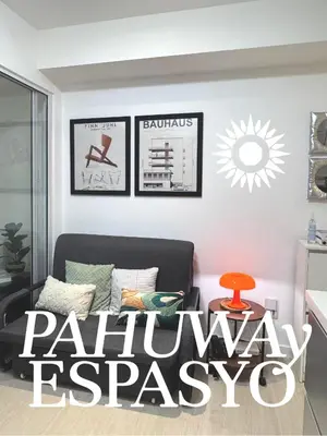 a living room with a black couch and paintings on the wall at Azure Bahamas by Pahuway Espasyo in Manila