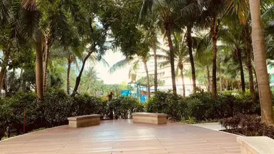 a walkway with benches and palm trees in a park at Azure Bahamas by Pahuway Espasyo in Manila