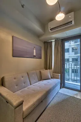a living room with a couch and a window at Minimalist Stay Mall of Asia WiFi, Netflix, Self Checkin in Manila