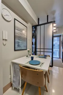 a dining room with a table and a clock on the wall at Minimalist Stay Mall of Asia WiFi, Netflix, Self Checkin in Manila