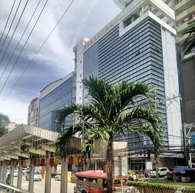 a palm tree in front of a tall building at Pristine Hotel in Manila