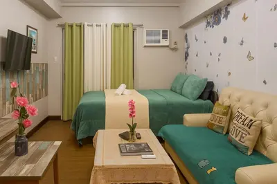 a living room with a couch and a living room with green curtains at La Suitez 1421 l Sky Studio l 360 City l Sea View in Manila