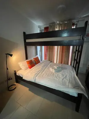 a bedroom with a bunk bed with white sheets and orange pillows at Makati City Antel Spa Residences 1615 in Manila