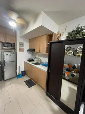 a kitchen with wooden cabinets and a refrigerator at Makati City Antel Spa Residences 1615 in Manila