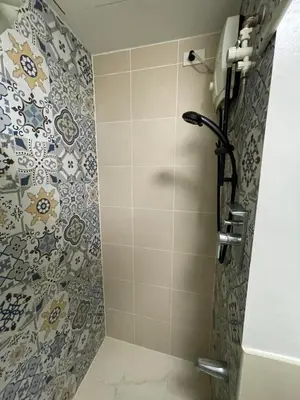 a bathroom with a shower with a tile wall at Makati City Antel Spa Residences 1615 in Manila