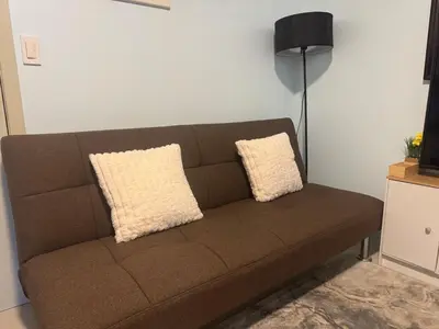 a brown couch in a living room with two pillows at Stylish Makati 2BR Condo with KTV and Awesome Pools! in Manila