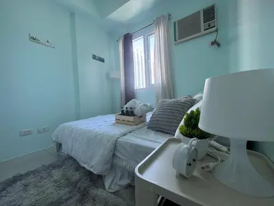 a bedroom with a bed and a desk and a window at Stylish Makati 2BR Condo with KTV and Awesome Pools! in Manila