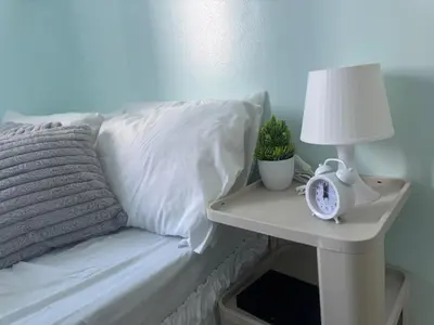 a bed with a lamp and a clock on a night stand at Stylish Makati 2BR Condo with KTV and Awesome Pools! in Manila