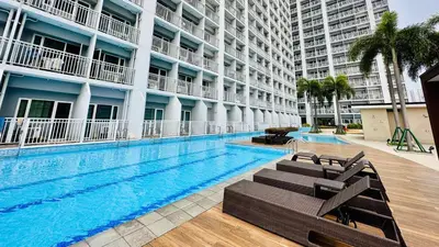 a swimming pool with chaise lounges next to a building at SMDC BREEZE RESIDENCES Pasay near AIRPORT PICC CCP WORLD TRADE CENTER MOA AND STARCITY in Manila