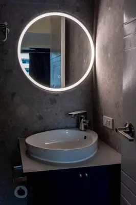 a bathroom with a sink and a round mirror at BGC Designer Pad Near Shops Dining Nightlife in Manila