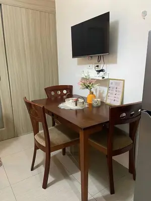 a wooden table with two chairs and a television on a wall at The Residence Suite in Manila