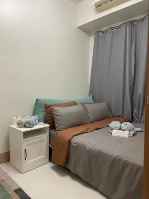 a bedroom with a bed with a table and a window at The Residence Suite in Manila
