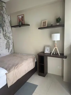 a bedroom with a bed and a table with a lamp at Relax Here! STUDIO TYPE in Manila
